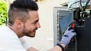 Ein Mann schraubt an einer Klimaanlage
