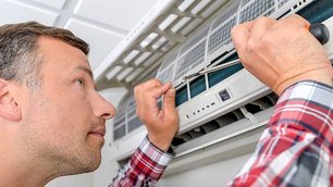 Mann untersucht eine Klimaanlage